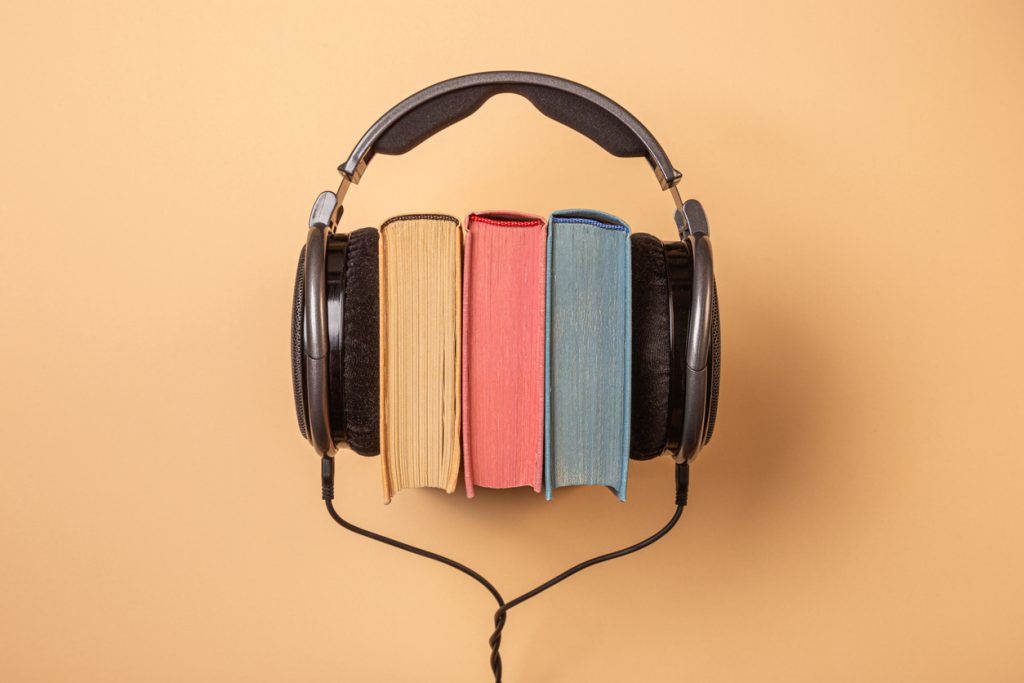 Ein Kopfhörer, der ein paar Bücher umarmt